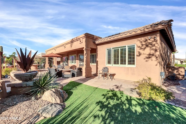 back of house with a patio area, an outdoor fire pit, and a lawn