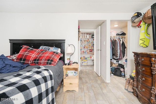 bedroom featuring a walk in closet, light wood-type flooring, and a closet