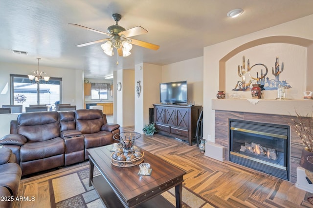 living room with ceiling fan with notable chandelier and parquet flooring