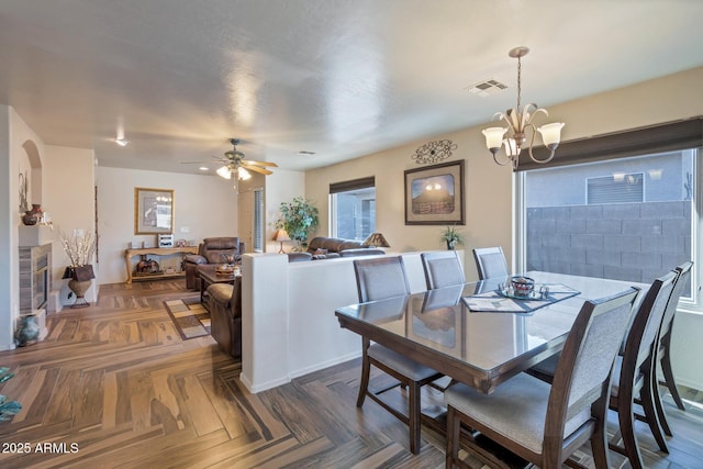 dining space with dark parquet floors and ceiling fan with notable chandelier