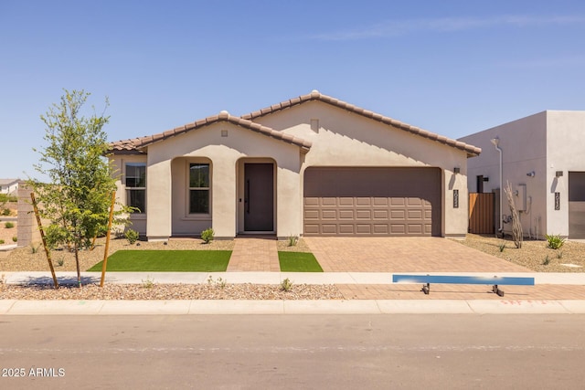 view of front of home with a garage, stucco siding, driveway, and a tile roof