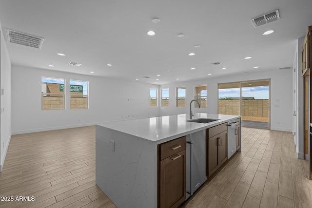 kitchen featuring visible vents, a healthy amount of sunlight, a sink, and light wood-style flooring