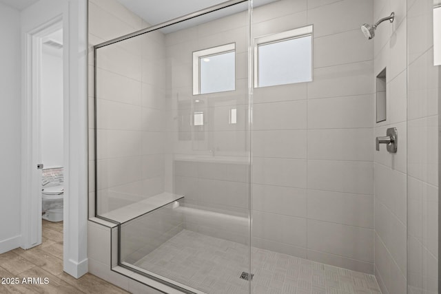 bathroom featuring toilet, wood finished floors, and a stall shower