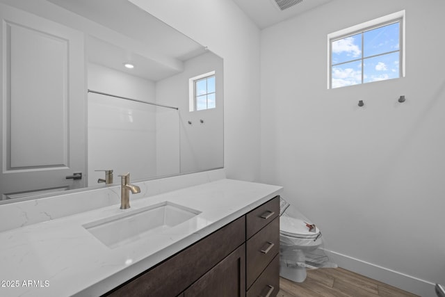 bathroom featuring visible vents, vanity, wood finished floors, toilet, and baseboards
