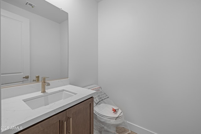bathroom with toilet, baseboards, visible vents, and vanity