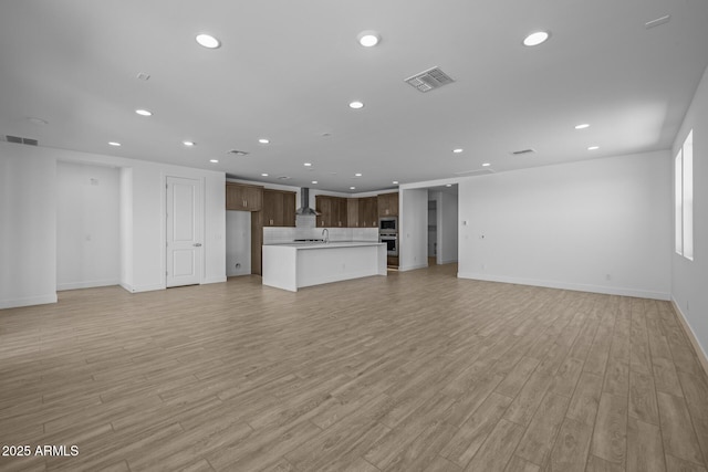 unfurnished living room featuring light wood-style floors, recessed lighting, and visible vents