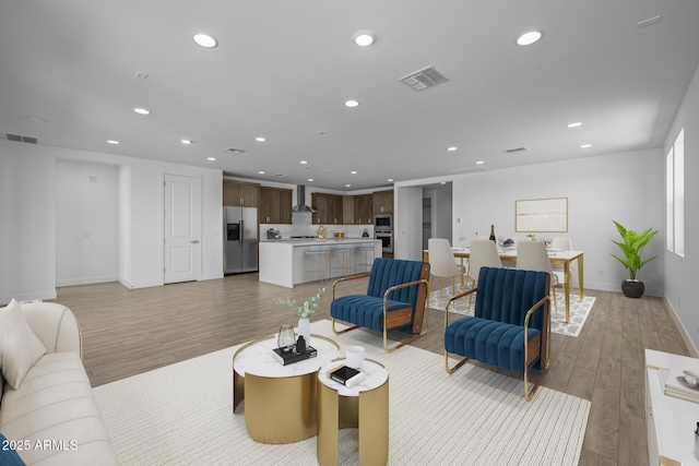 living room featuring light wood-style floors, baseboards, recessed lighting, and visible vents