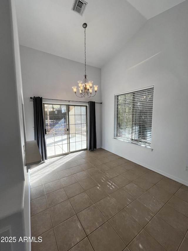 tiled spare room with a chandelier and vaulted ceiling