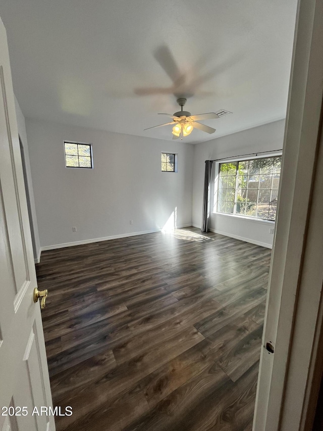 empty room with ceiling fan and dark wood-type flooring