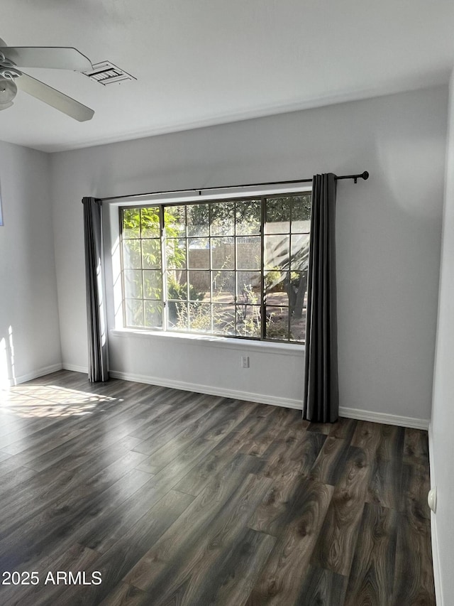 unfurnished room featuring ceiling fan, dark wood-type flooring, and a wealth of natural light