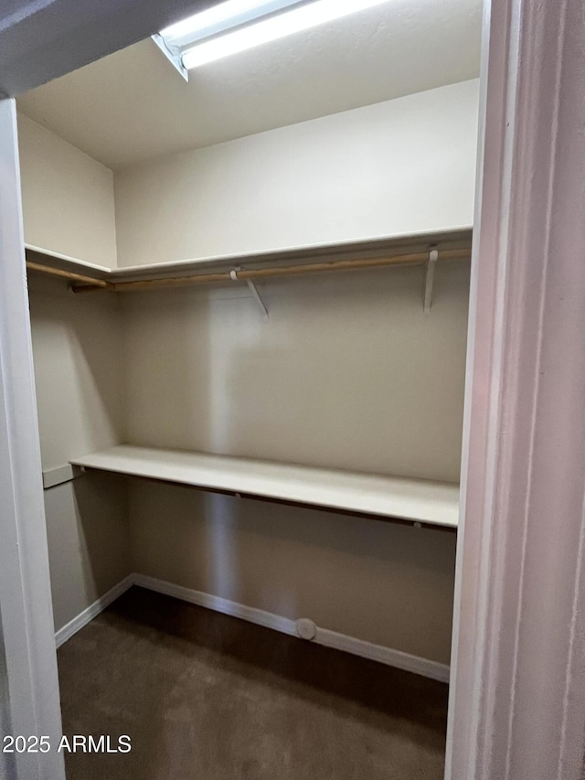 walk in closet featuring dark colored carpet