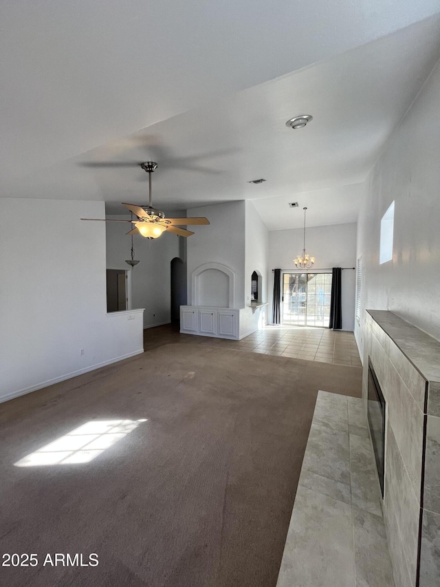 unfurnished living room with lofted ceiling, light carpet, a fireplace, and ceiling fan with notable chandelier