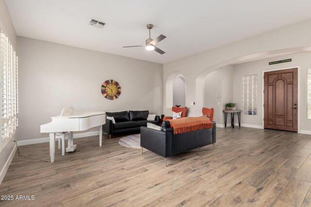 16201 S 29th Ave, Phoenix, AZ 85045 - living room with visible vents, a ceiling fan, baseboards, arched walkways, and light wood finished floors