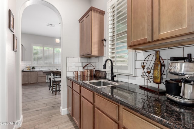 16201 S 29th Ave, Phoenix, AZ 85045 - kitchen featuring a sink, arched walkways, dark stone counters, tasteful backsplash, and visible vents
