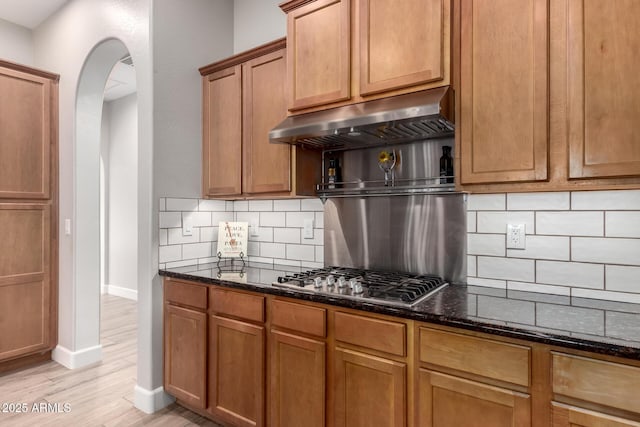 16201 S 29th Ave, Phoenix, AZ 85045 - kitchen with arched walkways, dark stone counters, stainless steel gas cooktop, and under cabinet range hood