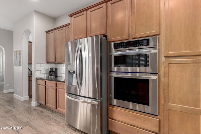 16201 S 29th Ave, Phoenix, AZ 85045 - kitchen featuring baseboards, arched walkways, light wood finished floors, backsplash, and stainless steel appliances