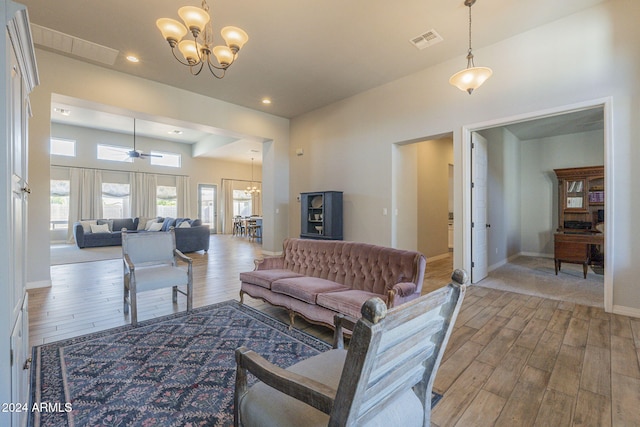 living room featuring light hardwood / wood-style floors and ceiling fan with notable chandelier