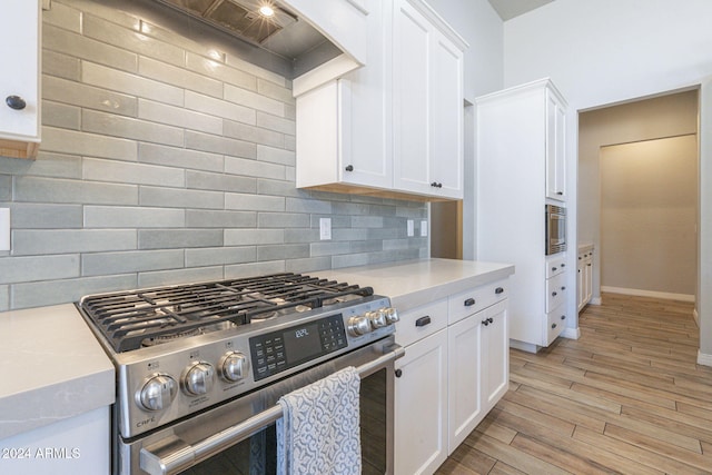 kitchen with white cabinetry, light wood-type flooring, appliances with stainless steel finishes, and tasteful backsplash