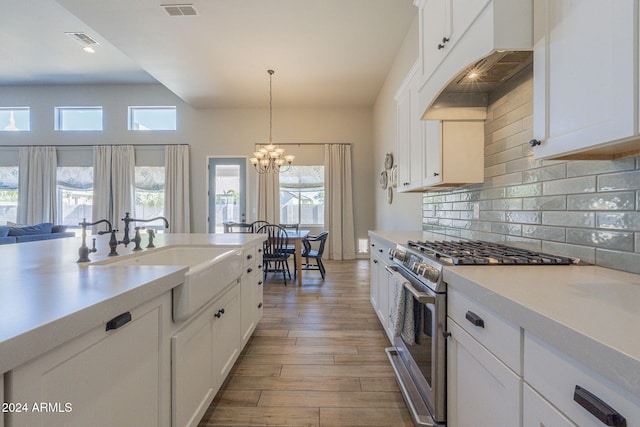 kitchen featuring hardwood / wood-style flooring, white cabinetry, sink, stainless steel stove, and pendant lighting