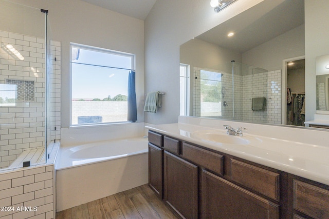 bathroom with independent shower and bath, vanity, wood-type flooring, and vaulted ceiling