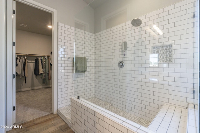 bathroom featuring hardwood / wood-style flooring and a tile shower