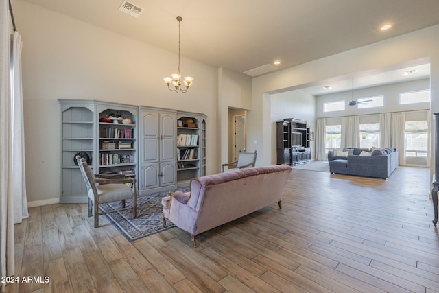 living room featuring a towering ceiling, an inviting chandelier, and light hardwood / wood-style floors