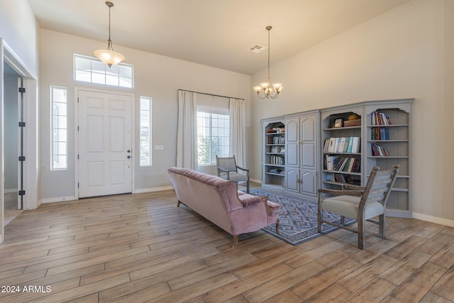 interior space with high vaulted ceiling, a notable chandelier, and light hardwood / wood-style flooring