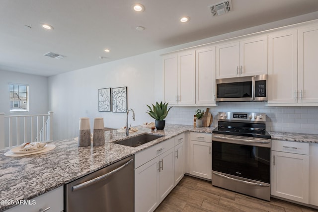 kitchen with hardwood / wood-style floors, sink, white cabinetry, and stainless steel appliances