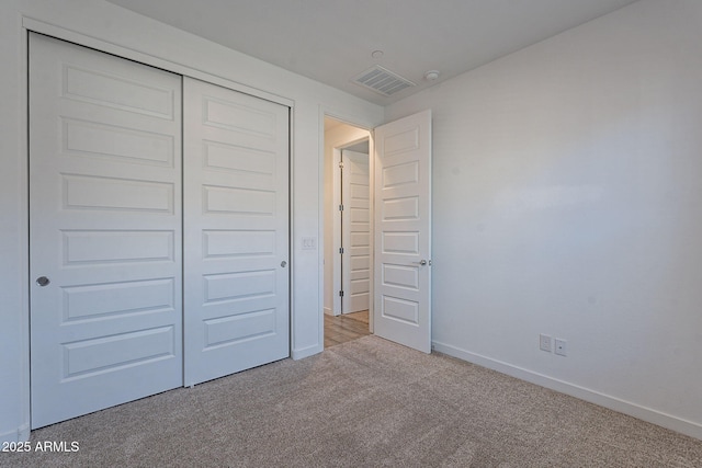 unfurnished bedroom featuring a closet and light colored carpet