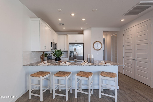 kitchen with white cabinets, a kitchen bar, kitchen peninsula, and stainless steel appliances