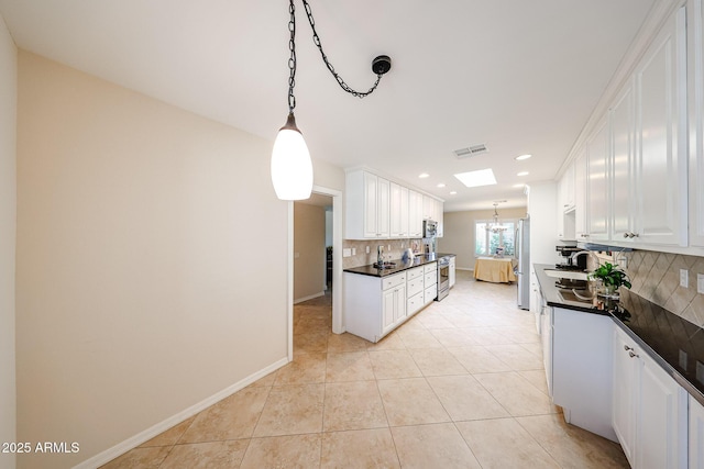 kitchen with stainless steel appliances, dark countertops, backsplash, white cabinetry, and recessed lighting