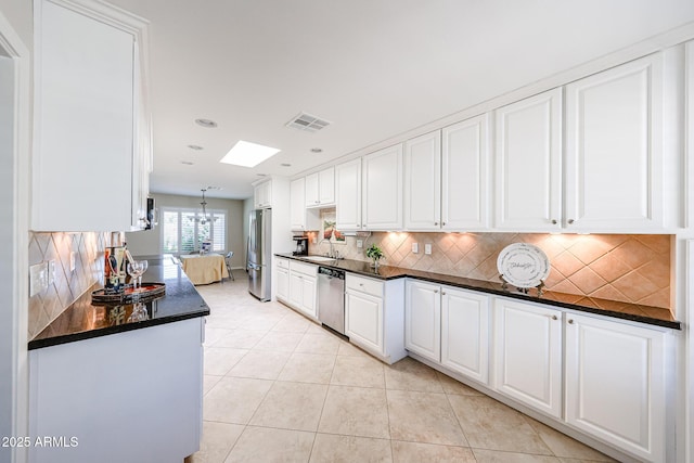 kitchen featuring appliances with stainless steel finishes, a sink, dark countertops, white cabinetry, and recessed lighting