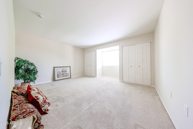 bedroom with two closets, carpet flooring, and baseboards