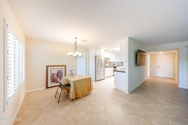 kitchen with freestanding refrigerator, a chandelier, light tile patterned floors, and healthy amount of natural light