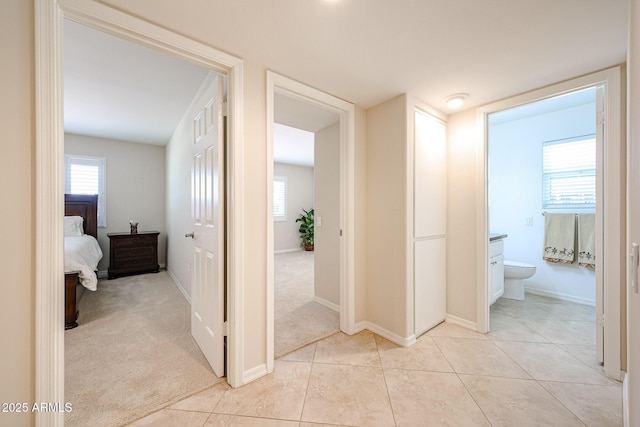hallway with healthy amount of natural light, baseboards, and light tile patterned flooring