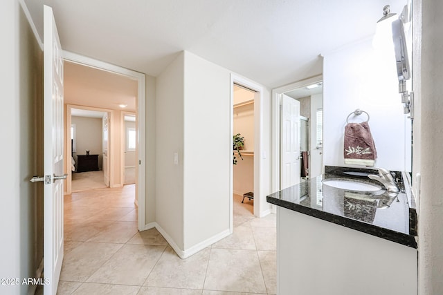 hallway featuring a sink, light tile patterned flooring, and baseboards