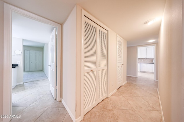 corridor featuring light tile patterned flooring and baseboards