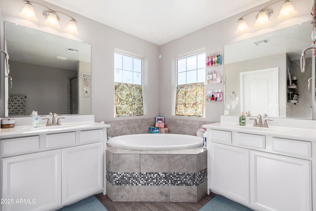 bathroom featuring hardwood / wood-style floors, a relaxing tiled tub, and vanity