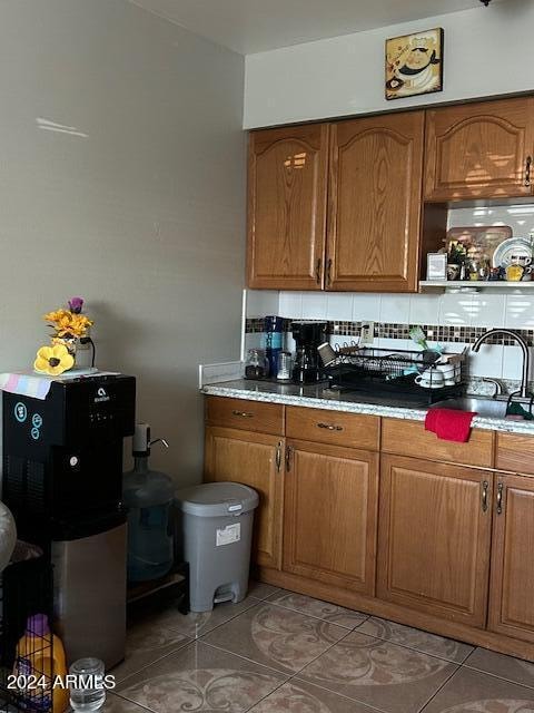 kitchen featuring tile patterned flooring, decorative backsplash, and sink