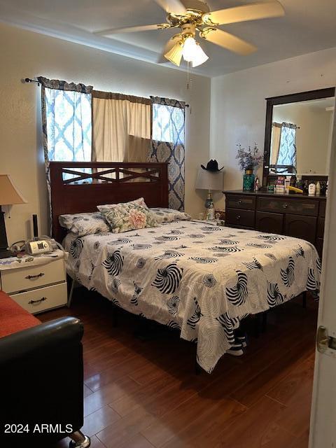 bedroom with multiple windows, wood-type flooring, and ceiling fan