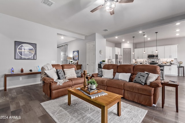 living room featuring ceiling fan, a barn door, and dark hardwood / wood-style floors