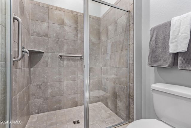 bathroom with a shower with shower door and toilet