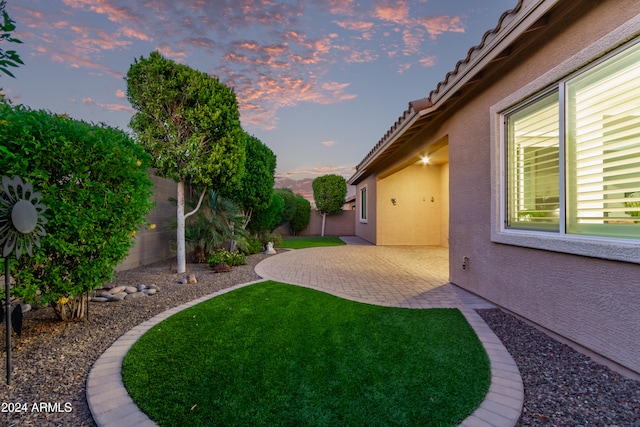 yard at dusk featuring a patio