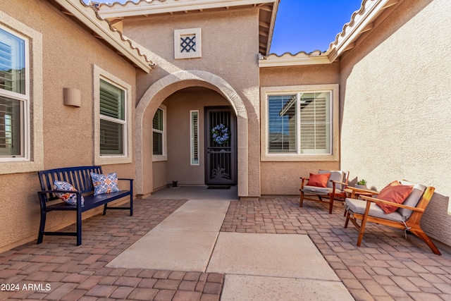 view of exterior entry with a patio and an outdoor living space