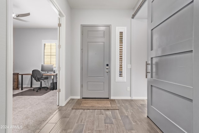 foyer entrance with ceiling fan and light hardwood / wood-style flooring