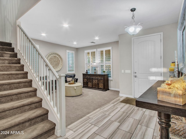 carpeted foyer entrance featuring a notable chandelier