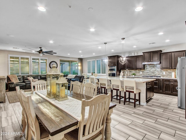 dining space with ceiling fan with notable chandelier and light wood-type flooring