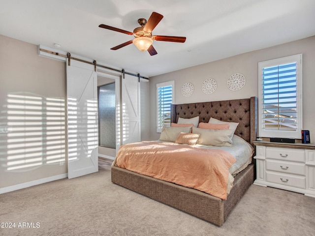 carpeted bedroom with ceiling fan and a barn door