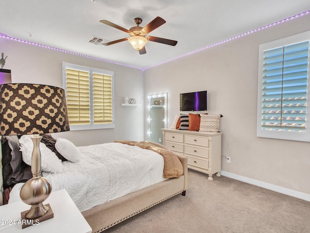 bedroom featuring ceiling fan, light carpet, and multiple windows