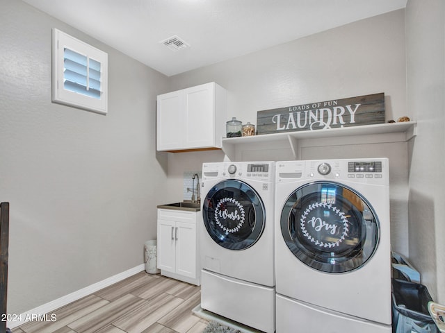 laundry room with cabinets, sink, light hardwood / wood-style flooring, and washing machine and clothes dryer